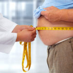 Doctor measuring obese man stomach.